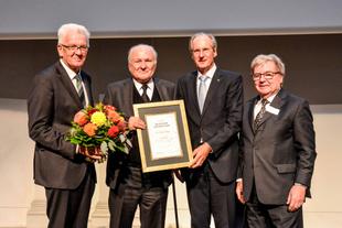 Vier festlich gekleidete Männer auf einer Bühne, Prof. Dr. Claus Hipp hält die Urkunde zum Deutschen CSR-Preis 2018.
