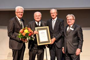 Vier festlich gekleidete Männer auf einer Bühne, Prof. Dr. Claus Hipp hält die Urkunde zum Deutschen CSR-Preis 2018.