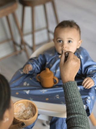 Little boy being fed porridge by mum