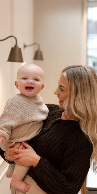 Mum holding baby both smiling