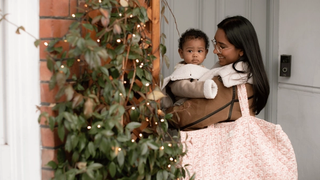 Mum carrying baby and a large bag outside a front door