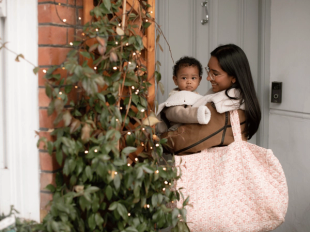 Mum carrying baby and a large bag outside a front door