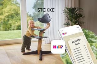 Lächelndes Baby am STOKKE Nomi Hochstuhl neben einem Smartphone mit HiPP App und Kassenbon