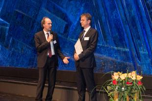 Juror Martin Oldeland überreicht Johannes Doms auf einer Bühne den Deutschen CSR-Preis 2017 für das HiPP-Werk Pfaffenhofen.