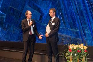 Juror Martin Oldeland überreicht Johannes Doms auf einer Bühne den Deutschen CSR-Preis 2017 für das HiPP-Werk Pfaffenhofen.