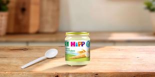 HiPP Bio-Gläschen „Reine Pastinaken“ ab dem 5. Monat mit Löffel auf einem Holztisch in heller Küchenatmosphäre