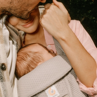 mum wearing baby whilst hugging partner