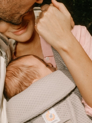 mum wearing baby whilst hugging partner