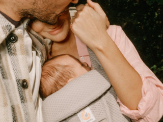mum wearing baby whilst hugging partner
