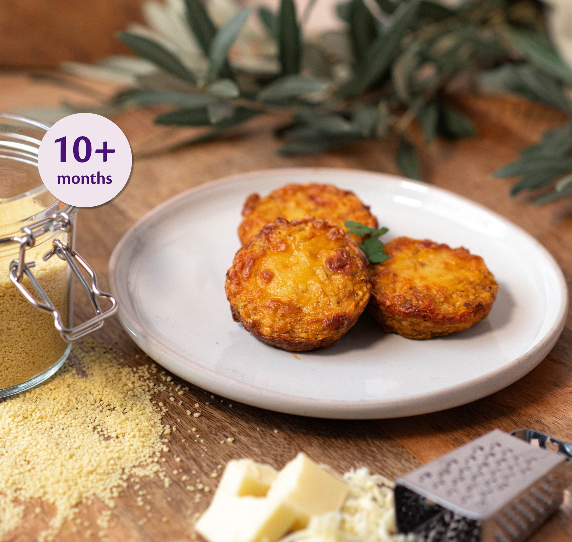 Three baked Bolognese cous cous bites on a white plate, shown as a finger food recipe suitable for babies 10+ months.