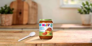 HiPP Bio Babygläschen Spaghetti Bolognese 190g auf Holztisch mit Löffel in heller, gemütlicher Küche