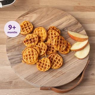 Mini sweet potato and apple waffles on a wooden board with apple slices, labelled suitable for babies 9+ months