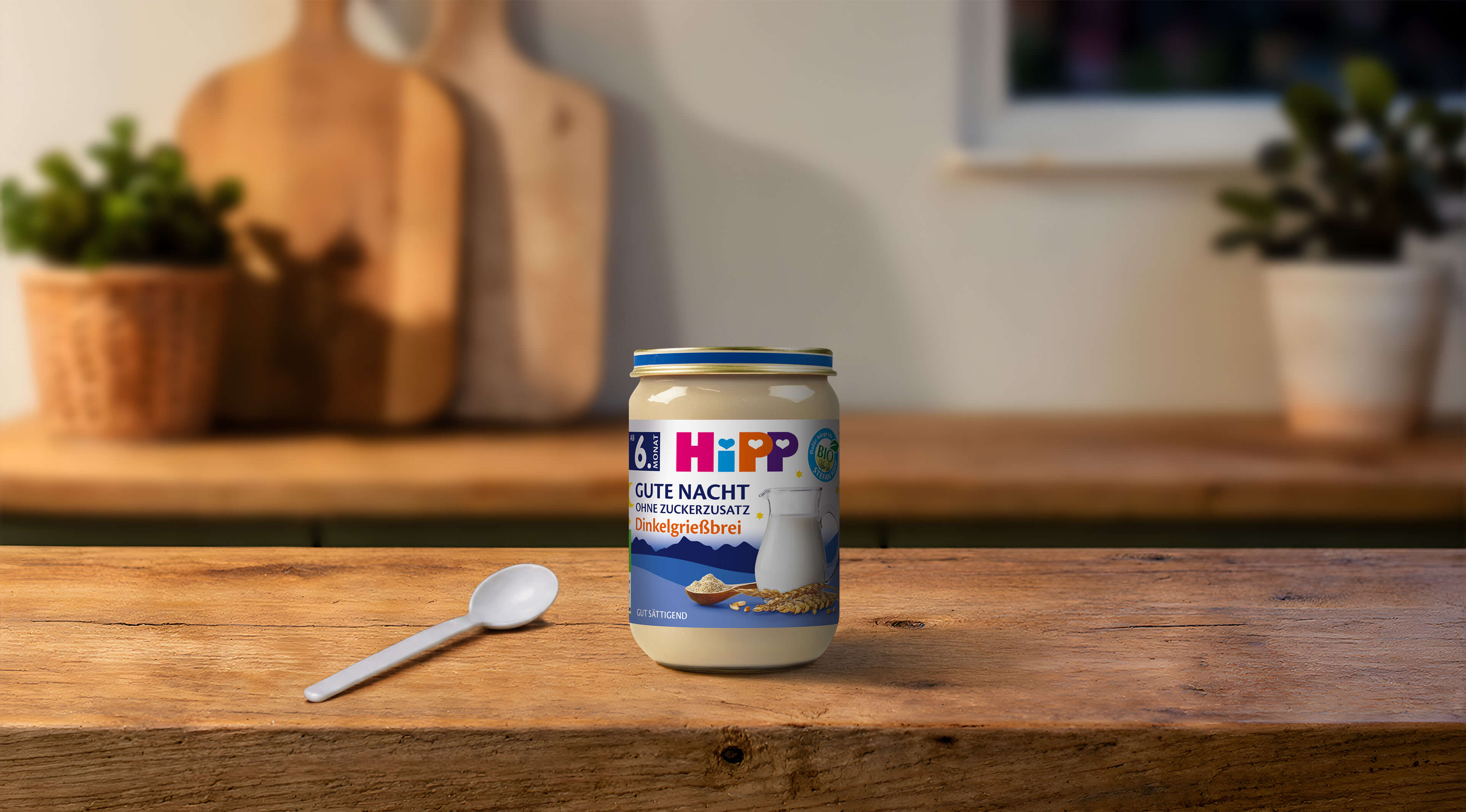 HiPP Gute Nacht Dinkelgrießbrei Bio-Gläschen ab 6. Monat ohne Zuckerzusatz mit Löffel auf warmer Küchenarbeitsplatte