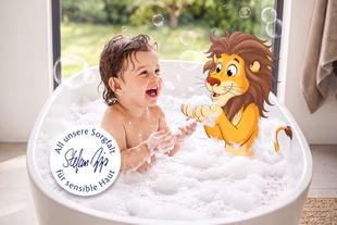 Lachendes Kleinkind badet mit animiertem Löwen im Schaum – sorgfältige Pflege für sensible Haut.