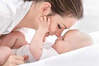Ein zärtlicher Moment zwischen einer Mutter und ihrem Baby, in dem die Mutter sanft das Gesicht des Babys berührt und damit Gefühle der Liebe und Verbundenheit hervorruft.