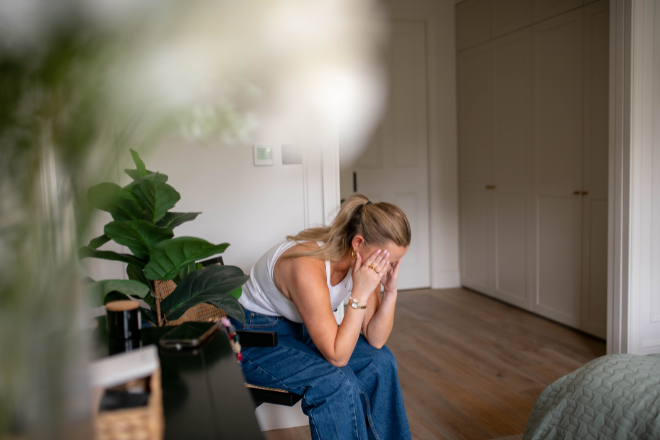Woman sat on chair in bedroom with head in hands