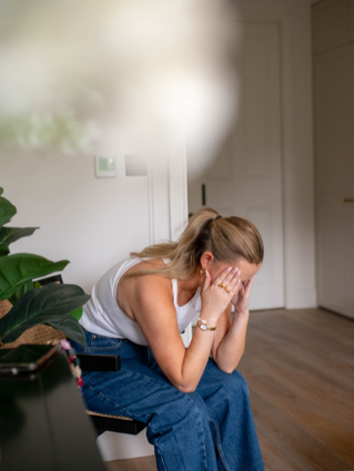 Woman sat on chair in bedroom with head in hands