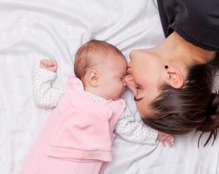 Ein zärtlicher Moment zwischen einer Mutter und ihrem Baby, in dem die Mutter sanft die Stirn des Babys küsst.