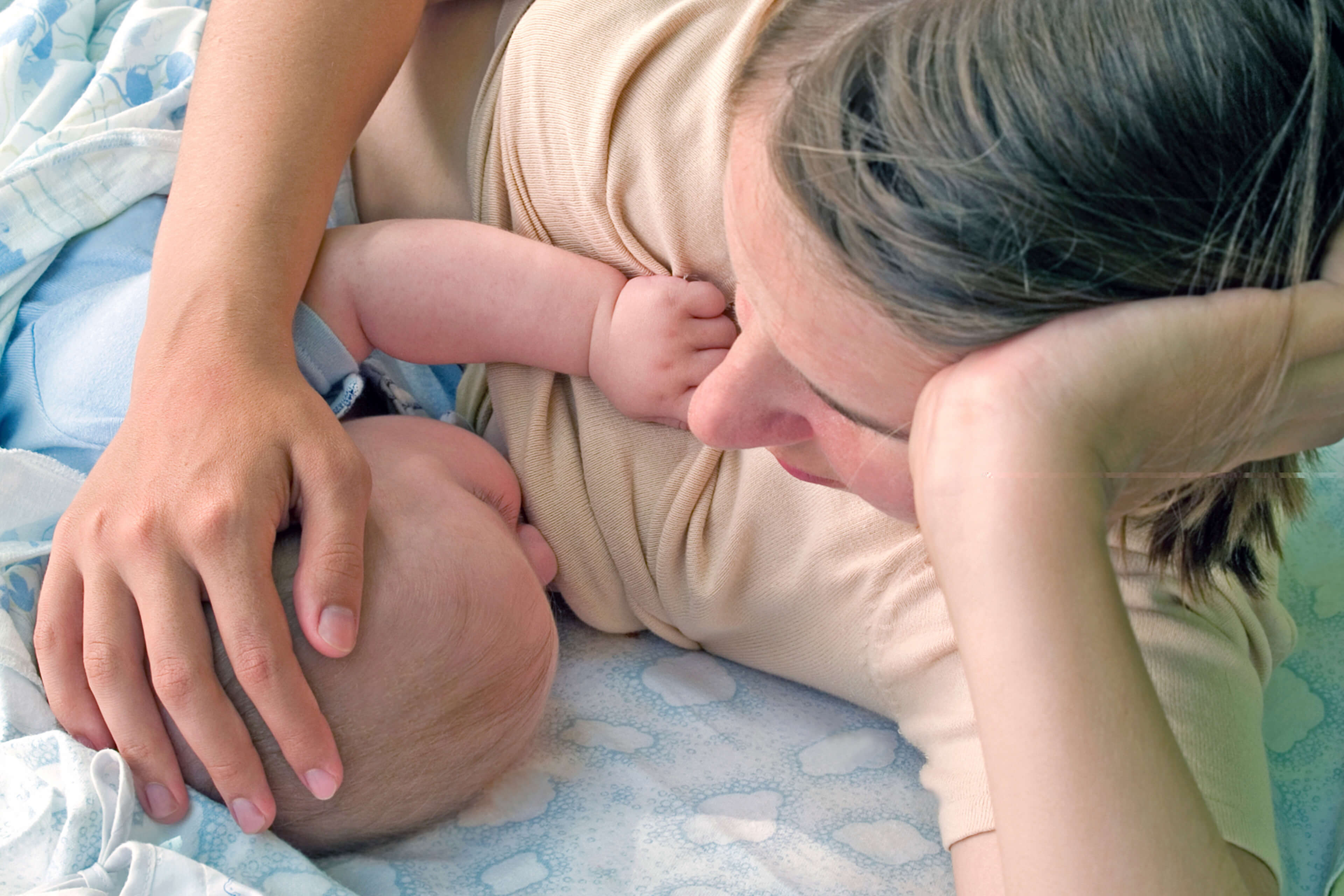 Die zärtliche Umarmung einer Mutter für ihr Baby, wobei die Hand der Mutter sanft auf dem Kopf des Babys ruht.