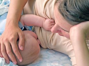 Die zärtliche Umarmung einer Mutter für ihr Baby, wobei die Hand der Mutter sanft auf dem Kopf des Babys ruht.