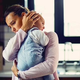 Mum looking stressed whilst rocking crying baby