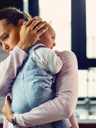 Mum looking stressed whilst rocking crying baby