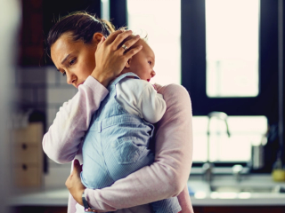 Mum looking stressed whilst rocking crying baby