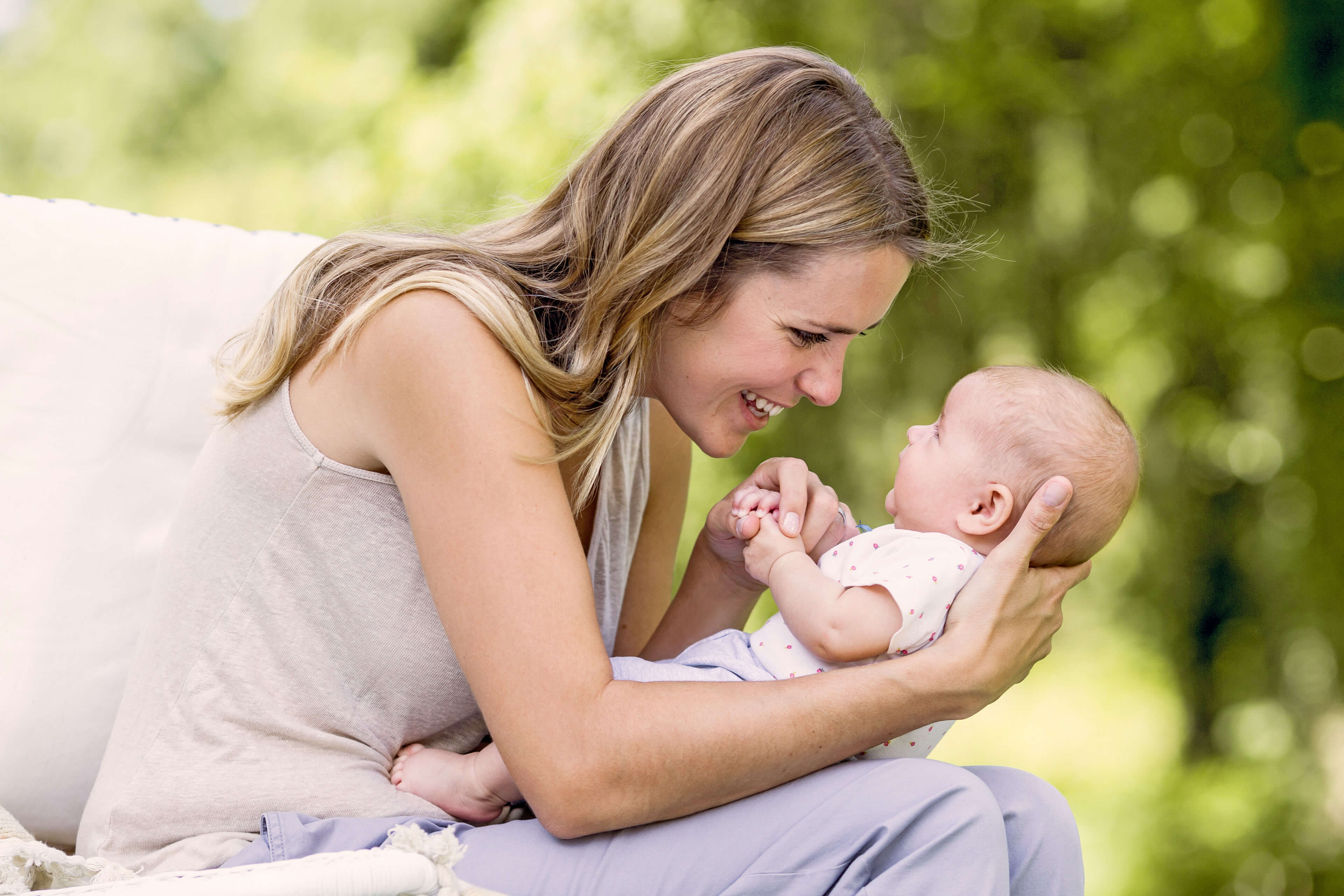 Ein zärtlicher Moment zwischen einer Frau und einem Baby, in dem die Frau das Baby im Arm hält und beide eine freudige Interaktion erleben.