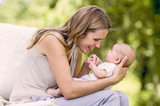 Ein zärtlicher Moment zwischen einer Frau und einem Baby, wobei die Frau das Baby dicht an ihr Gesicht hält und beide eine freudige Interaktion teilen.