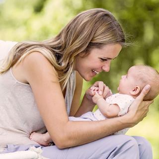 Ein zärtlicher Moment zwischen einer Frau und einem Baby, wobei die Frau das Baby dicht an ihr Gesicht hält und beide eine freudige Interaktion teilen.