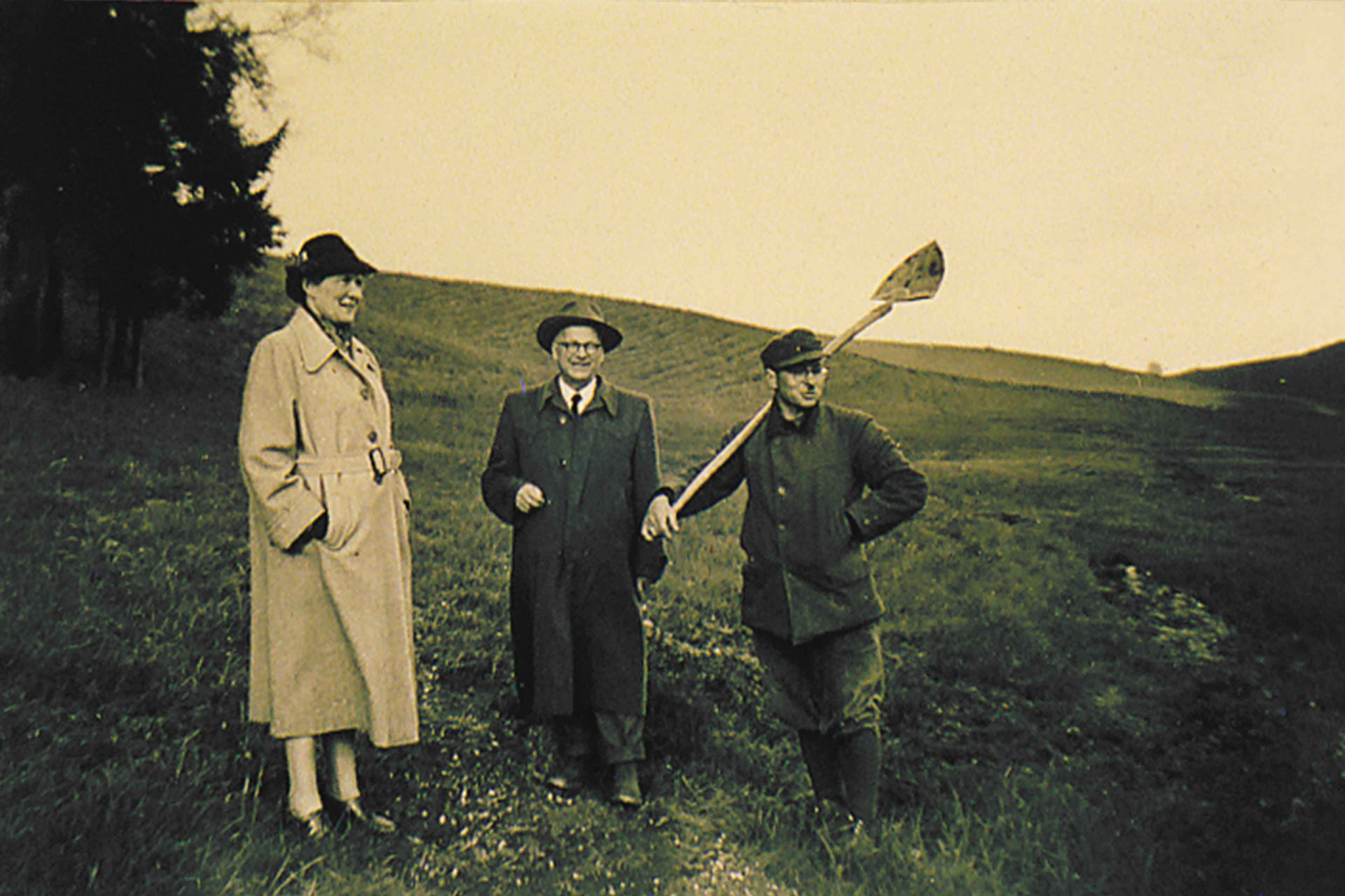 Historische Aufnahme von drei Personen auf dem Ehrensberger Hof, bei einem Rundgang über die grünen Bio-Wiesen von HiPP.