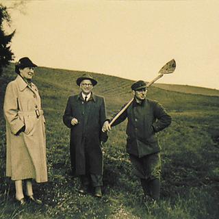 Historische Aufnahme von drei Personen auf dem Ehrensberger Hof, bei einem Rundgang über die grünen Bio-Wiesen von HiPP.
