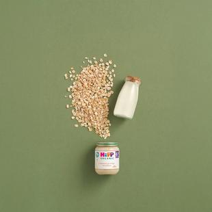 HiPP Organic Creamed Porridge Breakfast jar with oats and a bottle of milk on a green background