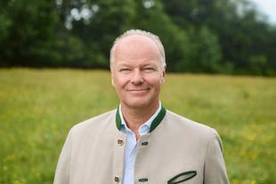 Stefan Hipp steht im Grünen auf einer Wiese und lächelt in die Kamera