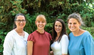 Lächelndes HiPP Elternservice-Team aus vier Frauen im Grünen, das Eltern persönlich und herzlich unterstützt