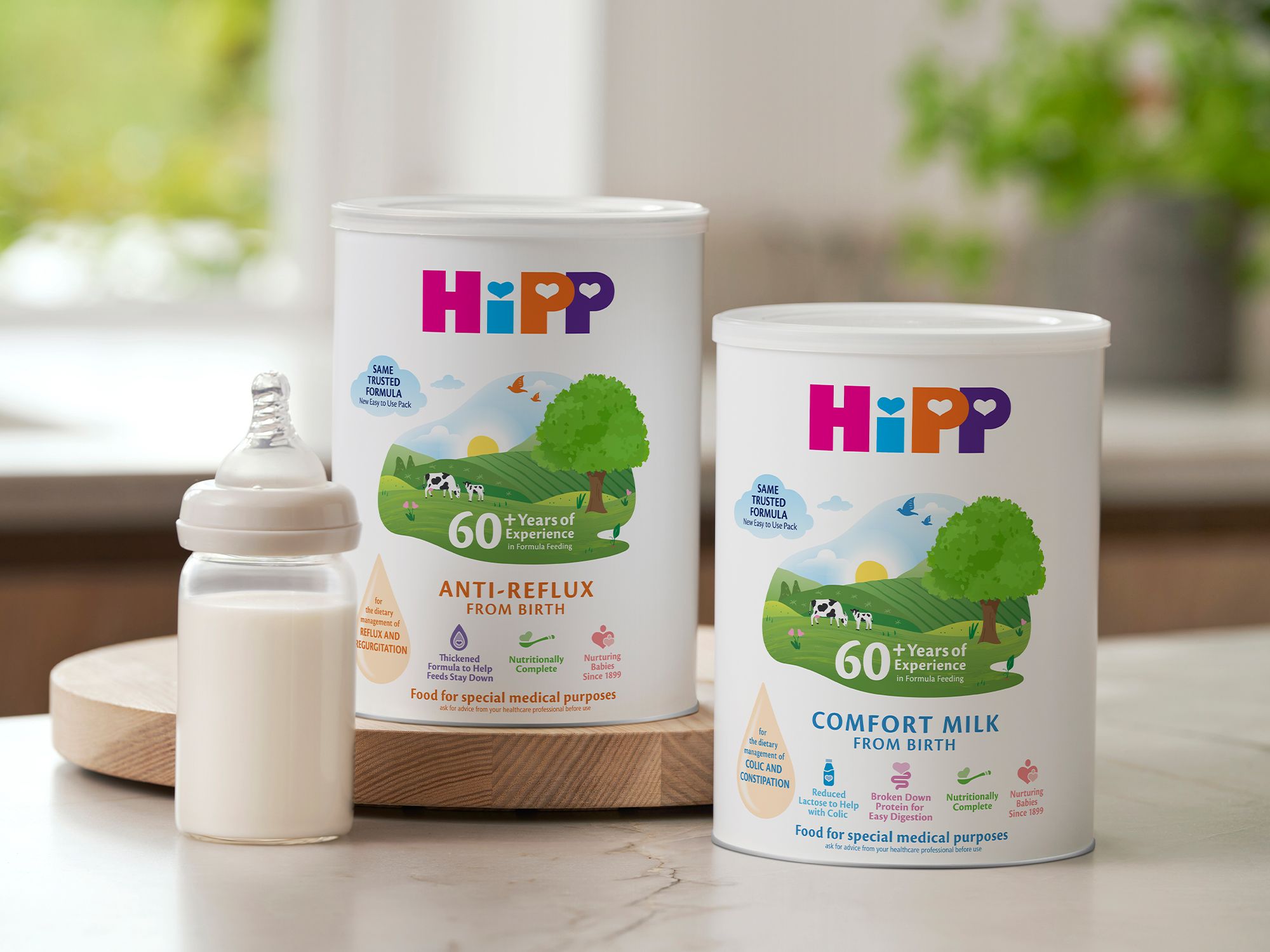 HiPP Organic comfort milk and anti‑reflux tins on a kitchen worktop beside a prepared baby bottle of formula
