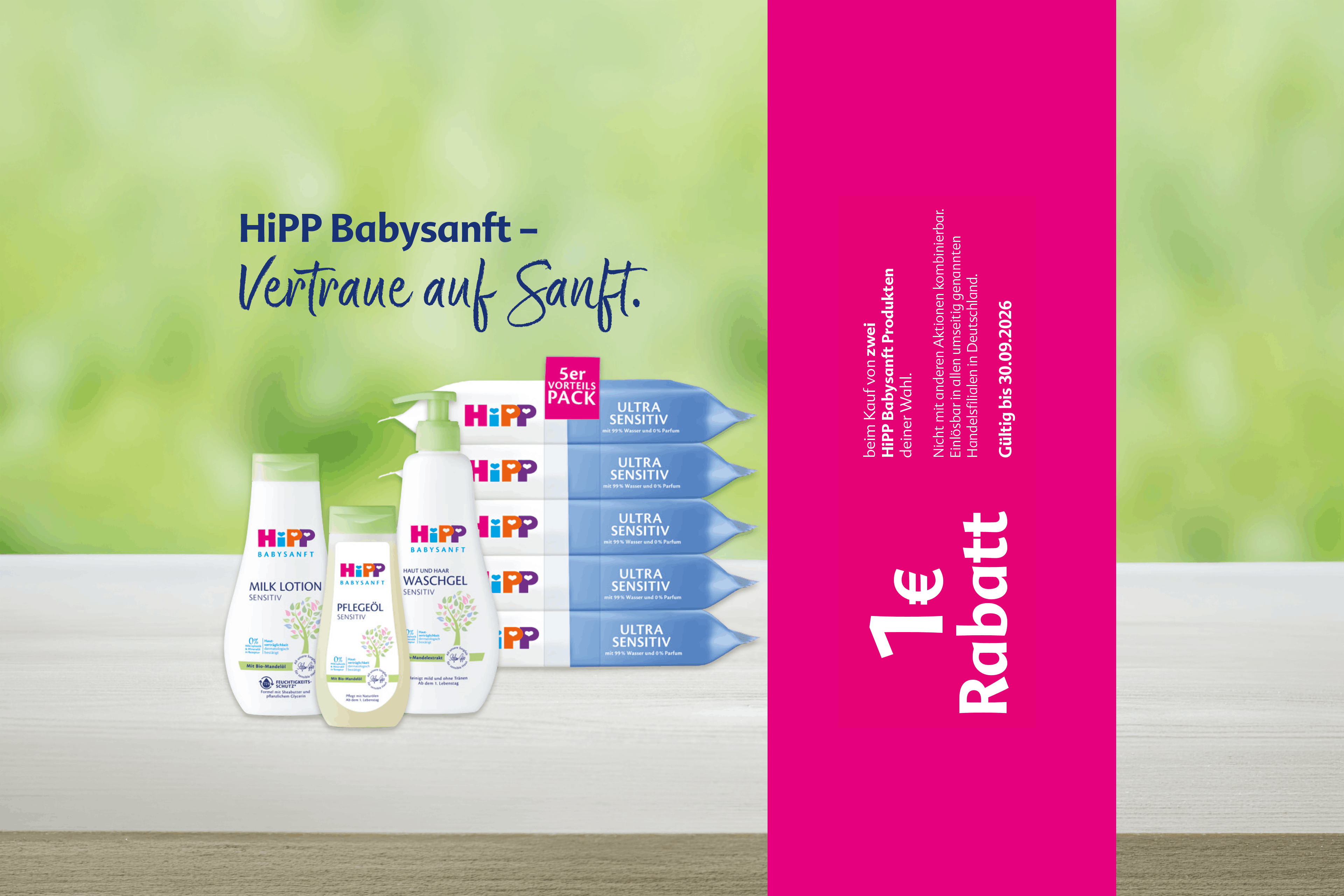 Mehrere HiPP Babysanft Pflegeprodukte stehen auf einer hellen Oberfläche vor grünem Hintergrund neben einem pinkfarbenen Streifen mit der Aufschrift '1 € Rabatt'