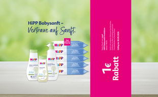Mehrere HiPP Babysanft Pflegeprodukte stehen auf einer hellen Oberfläche vor grünem Hintergrund neben einem pinkfarbenen Streifen mit der Aufschrift '1 € Rabatt'