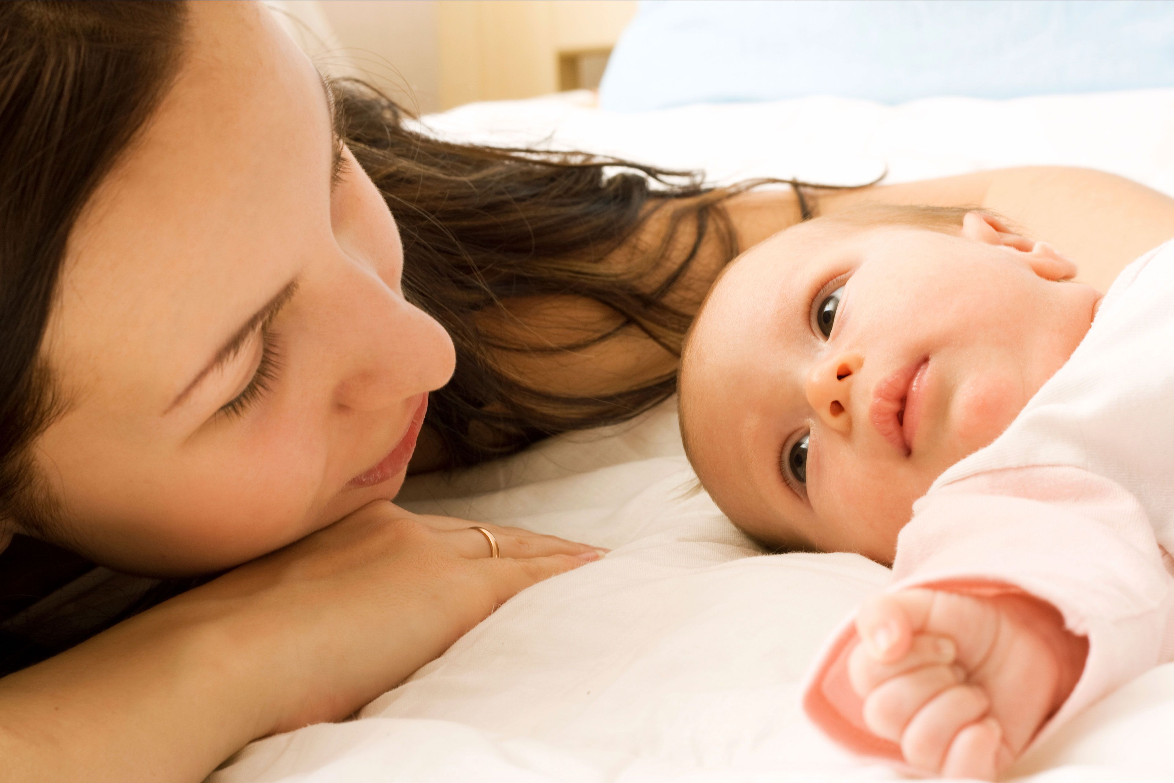 Ein zärtlicher Moment zwischen einer Frau und einem Baby, bei dem sich das Gesicht der Frau dem des Babys nähert und so ein Band der Liebe und Fürsorge zum Ausdruck bringt.