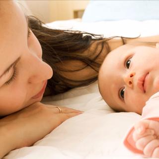 Ein zärtlicher Moment zwischen einer Frau und einem Baby, bei dem sich das Gesicht der Frau dem des Babys nähert und so ein Band der Liebe und Fürsorge zum Ausdruck bringt.
