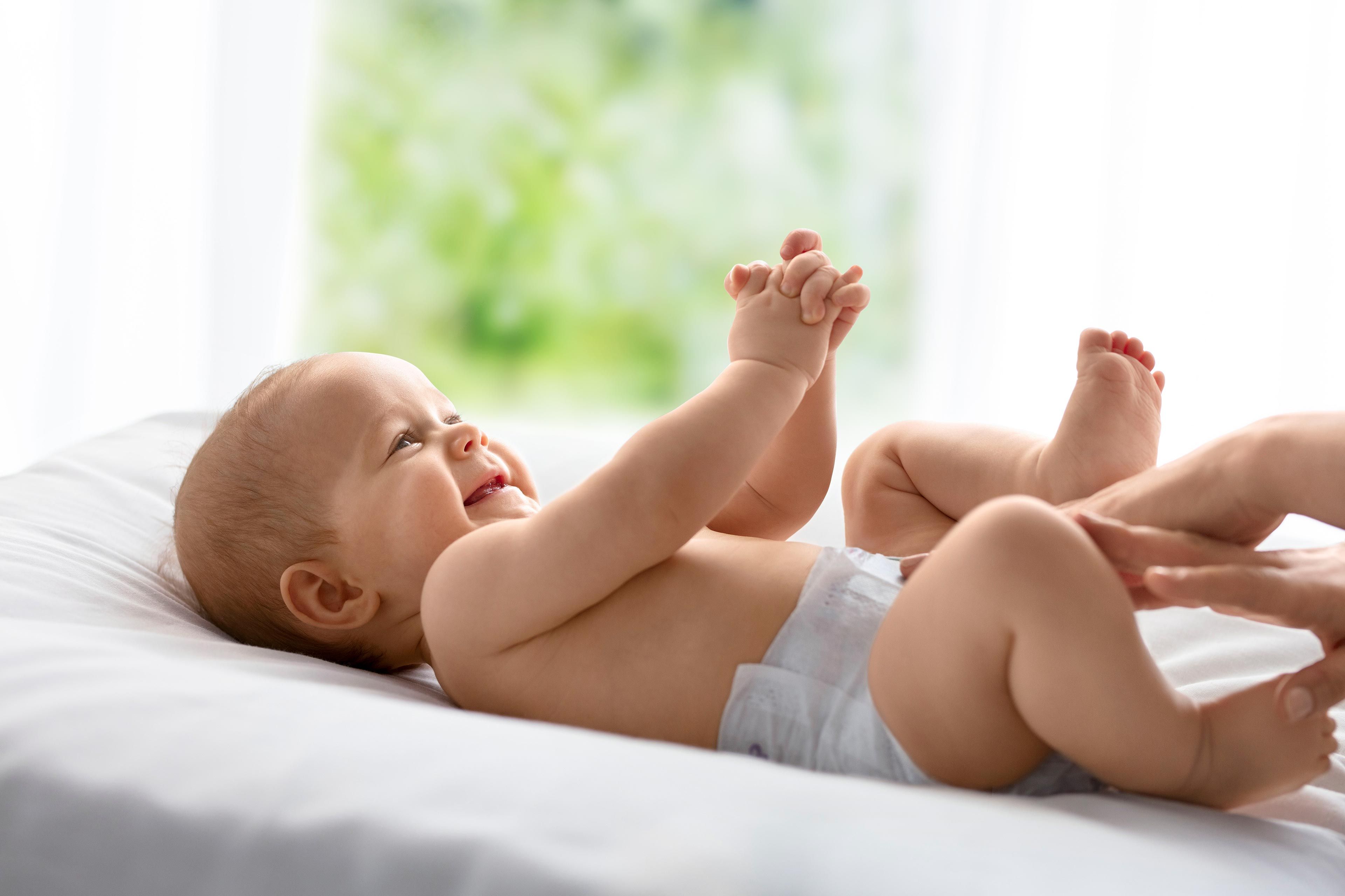 Baby liegt auf dem Rücken auf einer Wickelunterlage und hält seine Hände zusammen