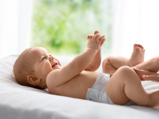 Baby liegt auf dem Rücken auf einer Wickelunterlage und hält seine Hände zusammen