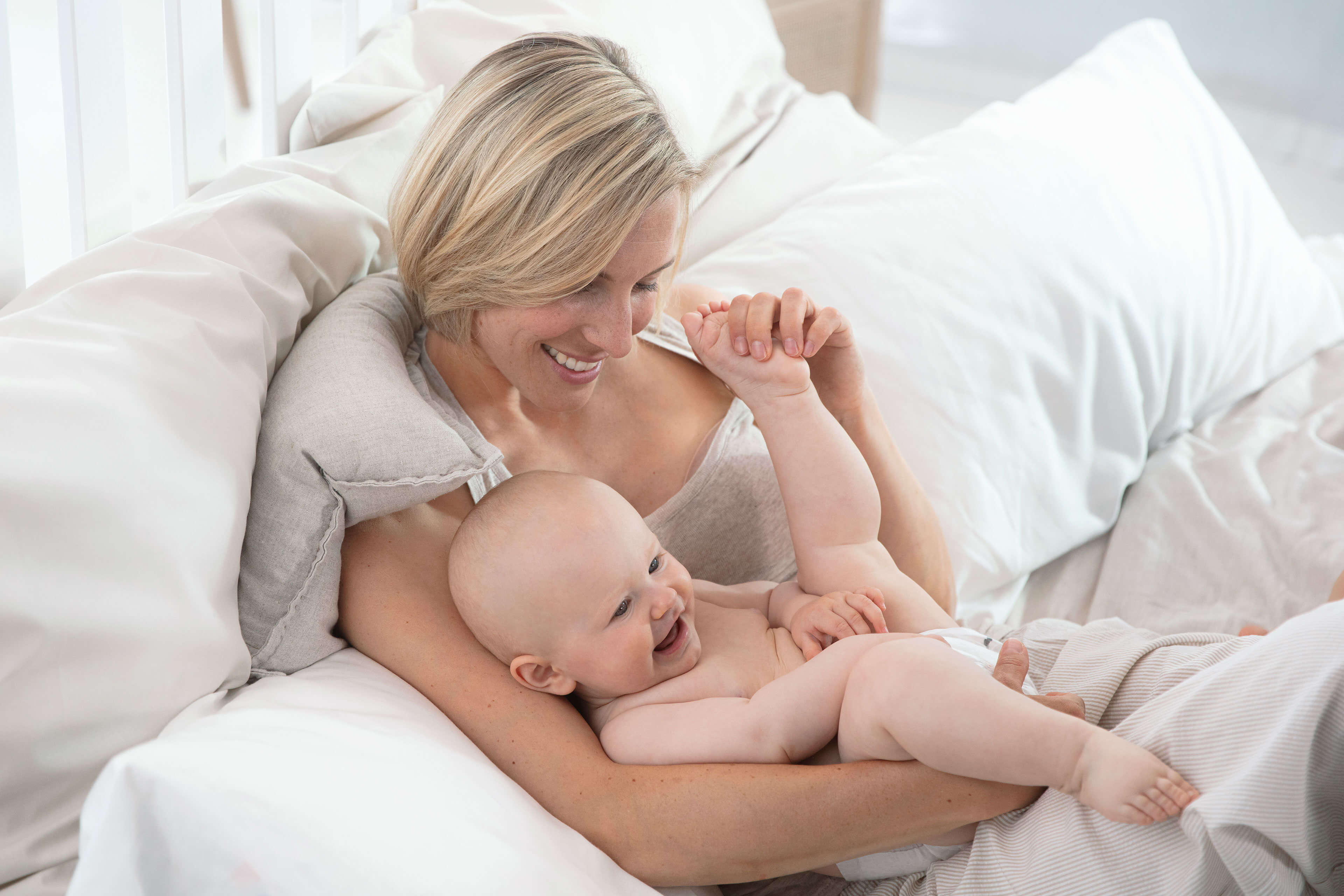 Ein freudiger Moment zwischen einer Mutter und ihrem Baby, in dem die Mutter spielerisch mit dem Fuß des Babys interagiert.
