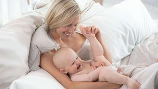 Ein freudiger Moment zwischen einer Mutter und ihrem Baby, in dem die Mutter spielerisch mit dem Fuß des Babys interagiert.