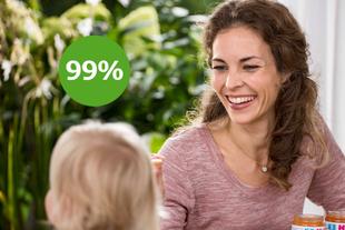 Lächelnde Mutter füttert ihr Baby mit HiPP 100% pflanzlich Spaghetti mit Linsen-Bolognese, daneben grüner Kreis mit „99 %“.