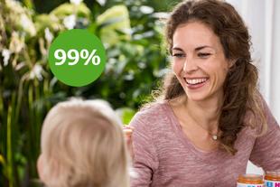Lächelnde Mutter füttert ihr Baby mit HiPP 100% pflanzlich Spaghetti mit Linsen-Bolognese, daneben grüner Kreis mit „99 %“.