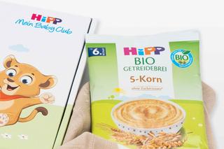 Verpackung von HiPP Bio-Getreidebrei Probebeutel 5-Korn neben HiPP Mein Baby Club-Box mit Löwenillustration