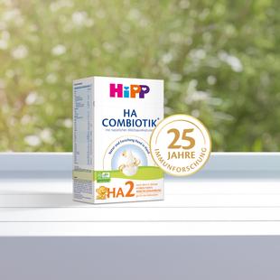 Packung HiPP HA 2 Combiotik mit Siegel "25 Jahre Immunforschung" vor unscharf grünem Hintergrund