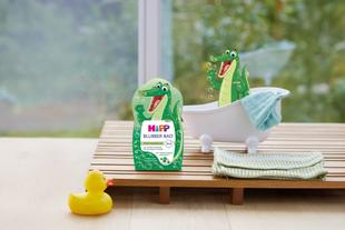 Kinderbad mit grünem Krokodilmotiv. Ein Krokodil sitzt in einer kleinen weißen Badewanne neben einem gelben Gummienten-Spielzeug