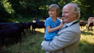 Stefan Hipp carrying his son, looking at cows in a field